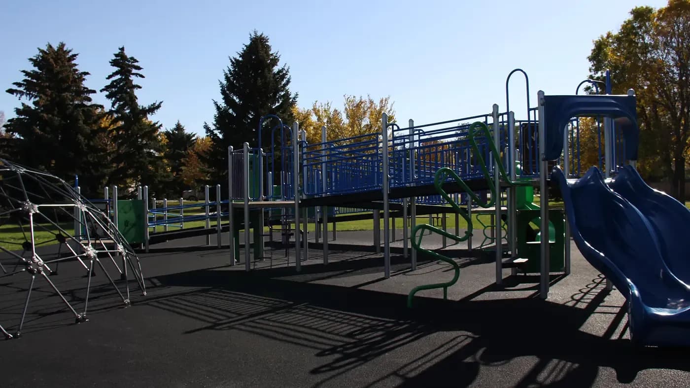 School playground with climbing structures on a black poured rubber surface